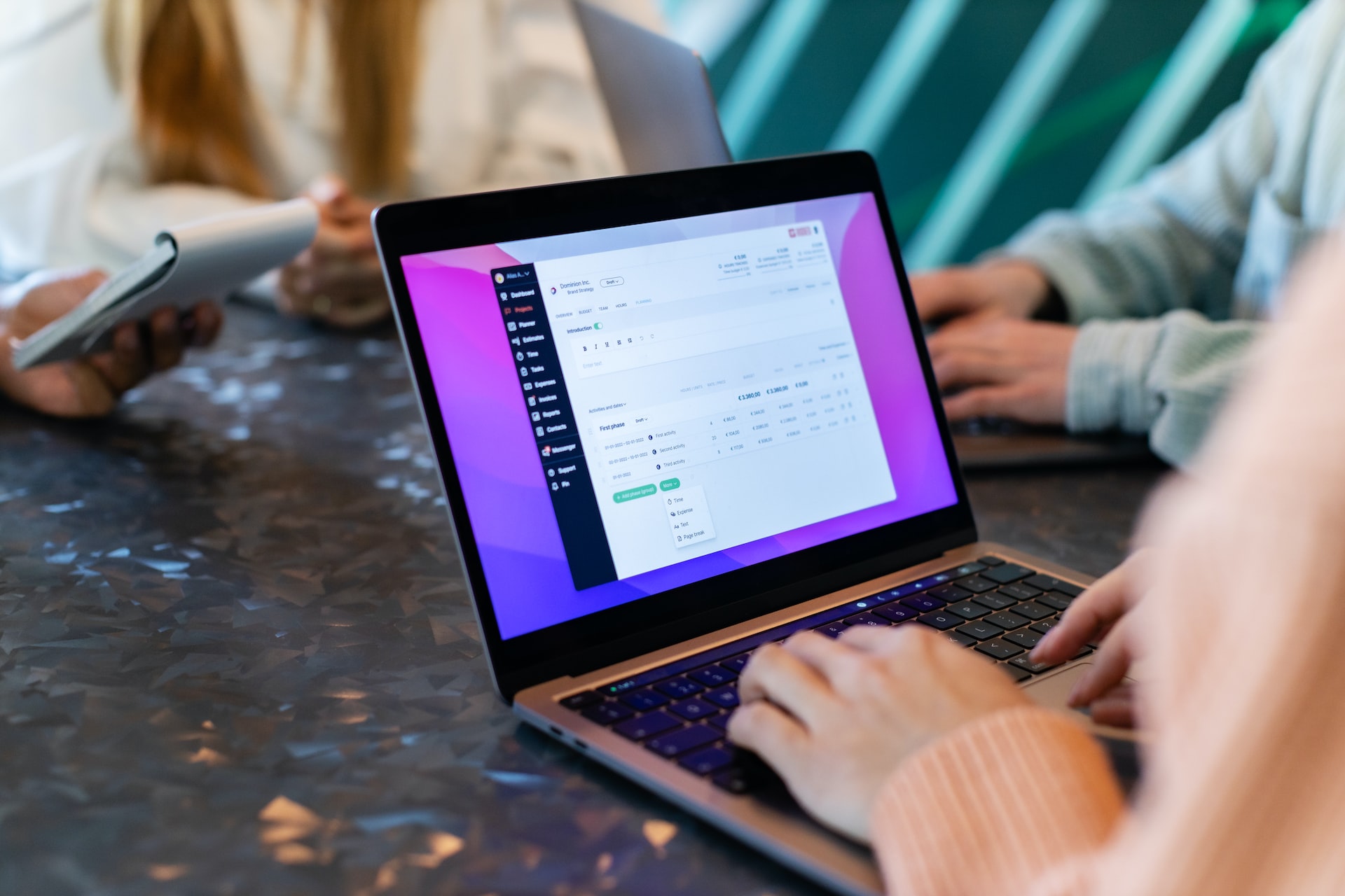 a group of people sitting at a table with laptops